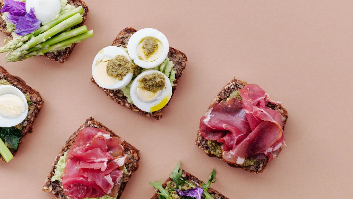 Delicious open-faced sandwiches with gourmet toppings including eggs, ham, and asparagus on rustic bread.